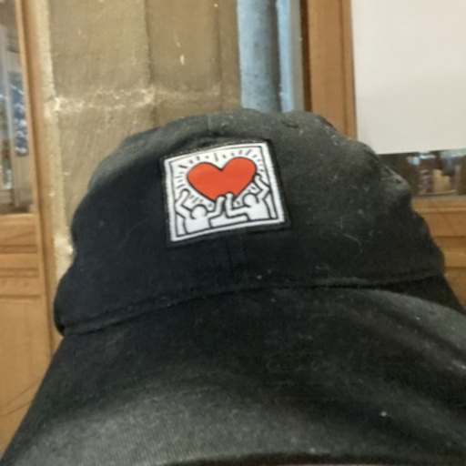 A black baseball cap with Keith Haring's 'Untitled, 1982' embroidered on it.